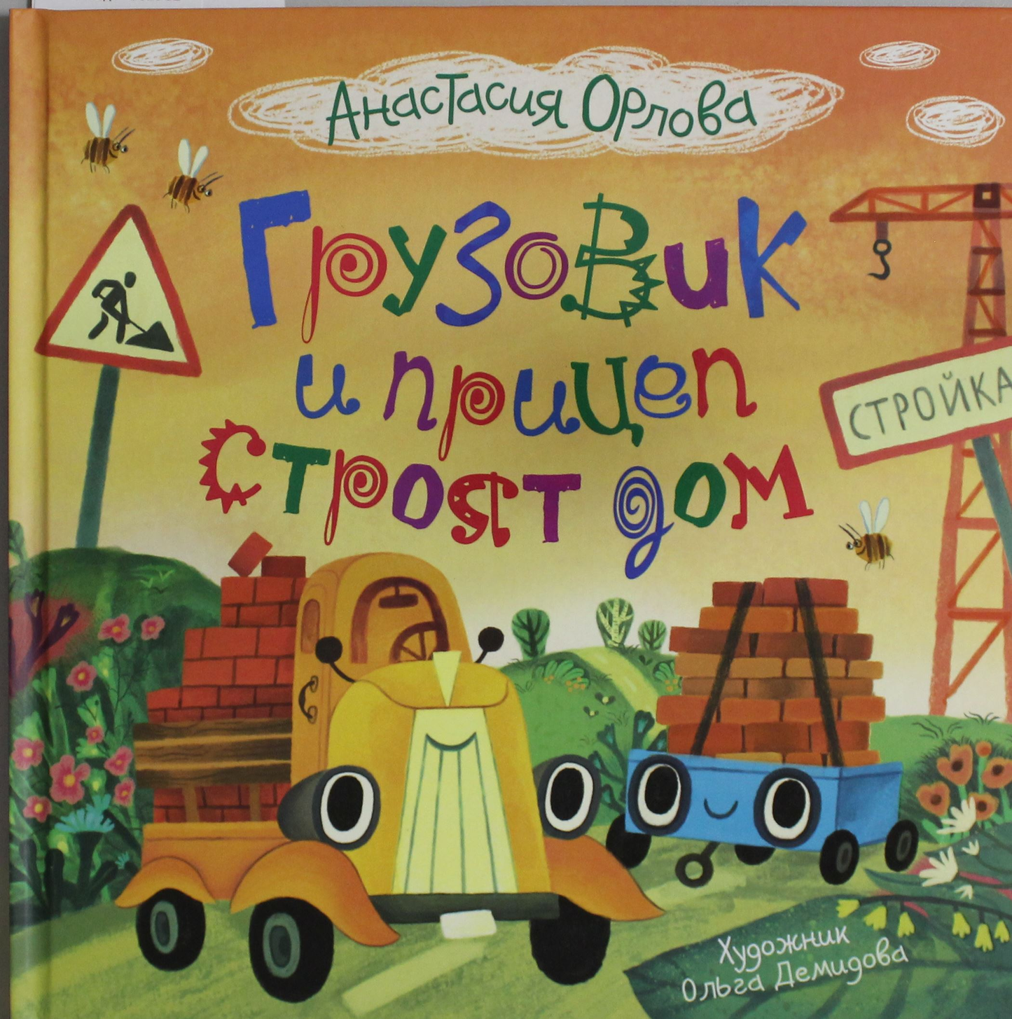 Детская книга "Грузовик и прицеп строят дом" от SOVABOOKS с иллюстрациями грузовика и строительных работ.