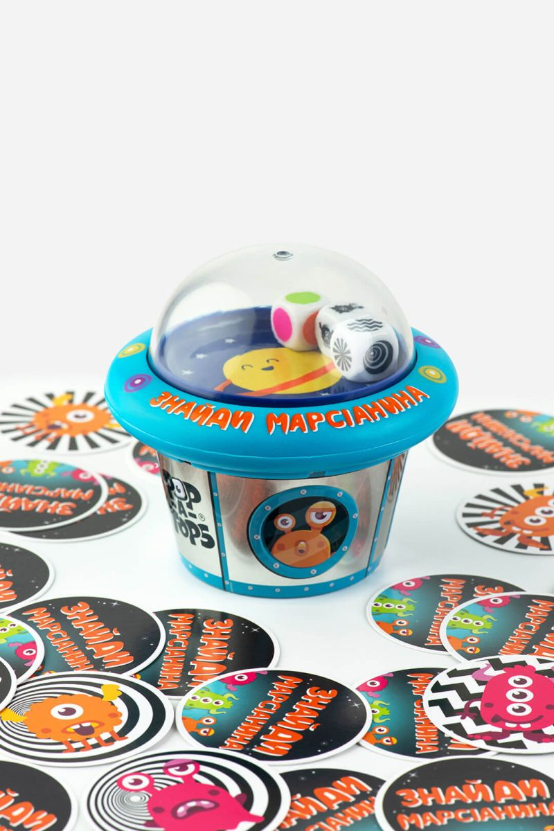 Настольная игра Pop-A-Tops: Знайди марсіанина от SOVABOOKS для детей, изображение коробки с яркими иллюстрациями и марсианином.